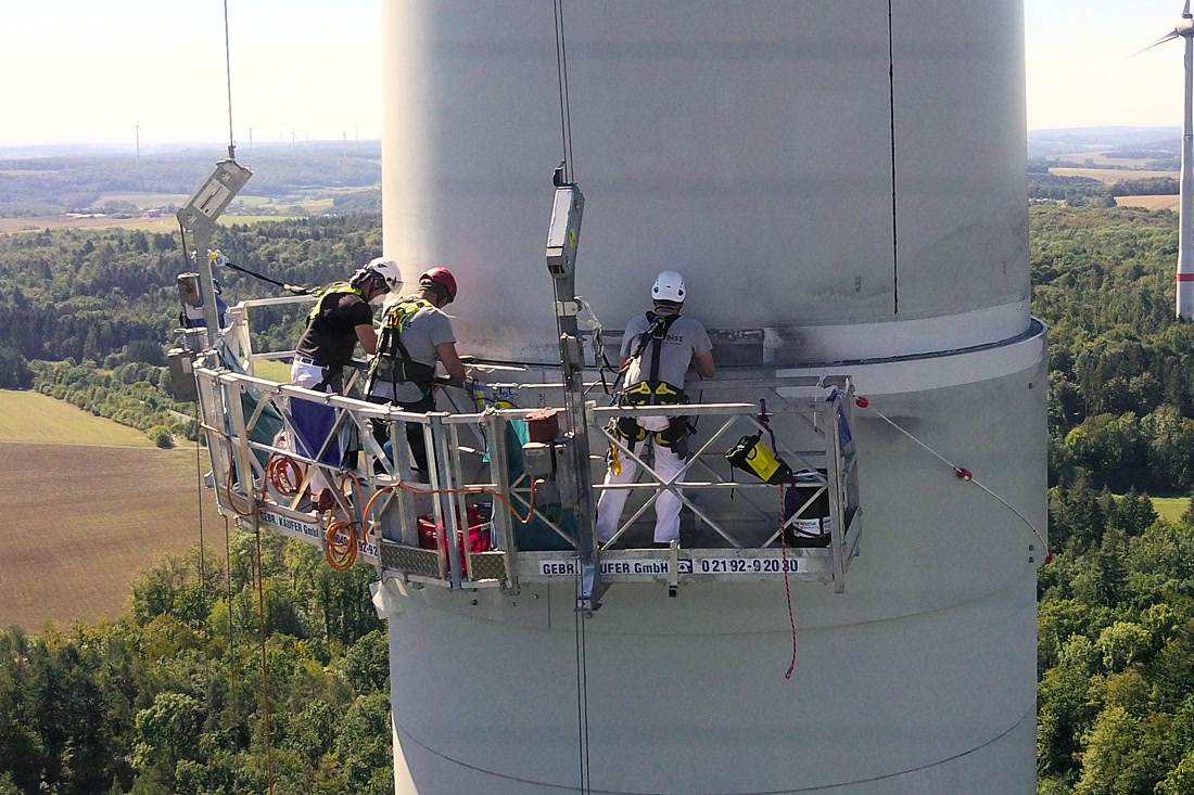Arbeiter im Arbeitskorb am Turm einer Windenergieanlage